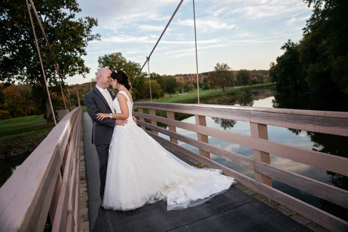 Groom hugs bride on a bridge at a Hudson Valley Wedding At West Hills Country Club In Middletown, New York
