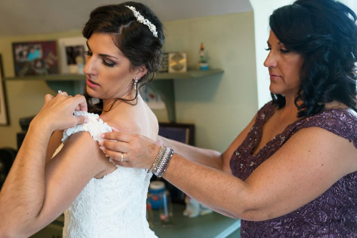 Mother helps bride into her wedding dress before her Hudson Valley Wedding At West Hills Country Club In Middletown, New York