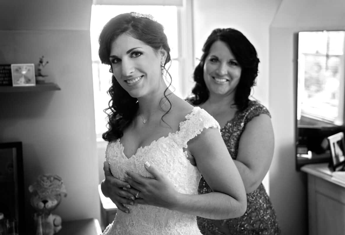 Mother helps bride her daugter into her wedding dress before her Hudson Valley Wedding At West Hills Country Club In Middletown, New York