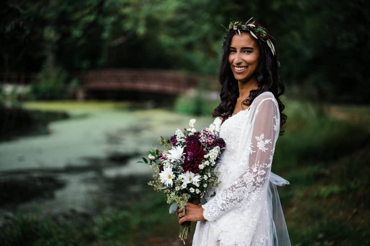 Bride poses with flowers by a bridge before her Hudson Valley wedding