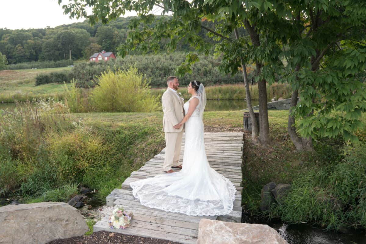 Bride and groom hold hands on bridge at Hudson Valley Wedding at Nostranos Vineyard
