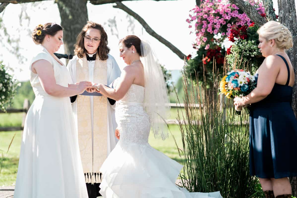 Bride puts ring on brides hand at Hudson Valley same sex wedding At Lippincott Manor in Walkill New York