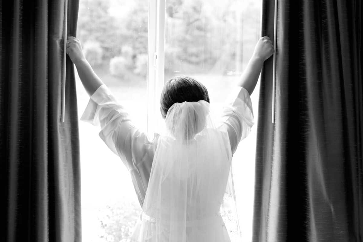Bride looks out window while shes getting ready for her Hudson Valley same sex wedding At Lippincott Manor in Walkill New York