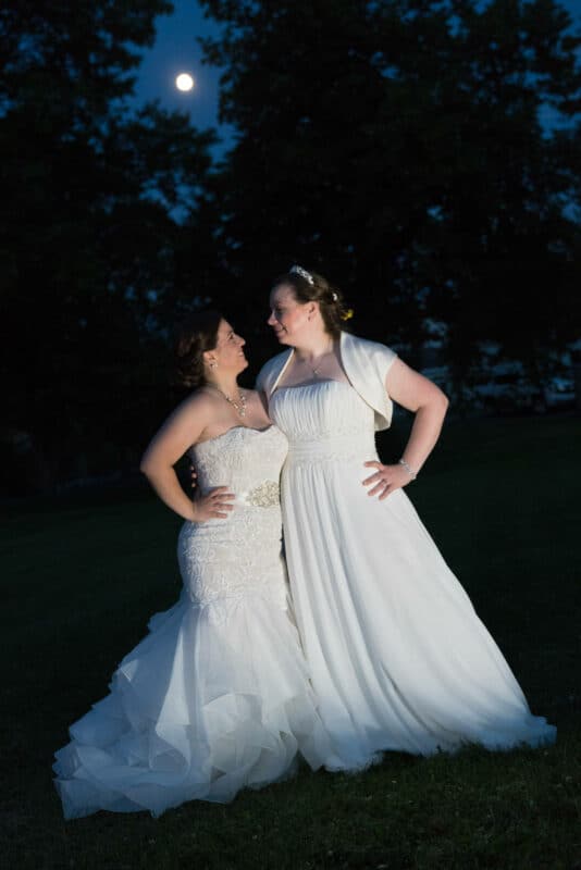 Bride and bride pose for photo by moon at Hudson Valley same sex wedding At Lippincott Manor in Walkill New York