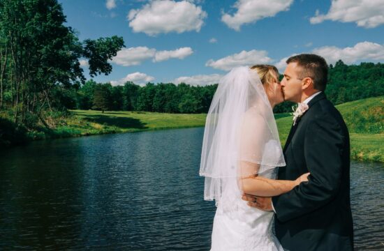Bride and grooms kiss by lake at their Albany Wedding at Sweet Basile Restaurant