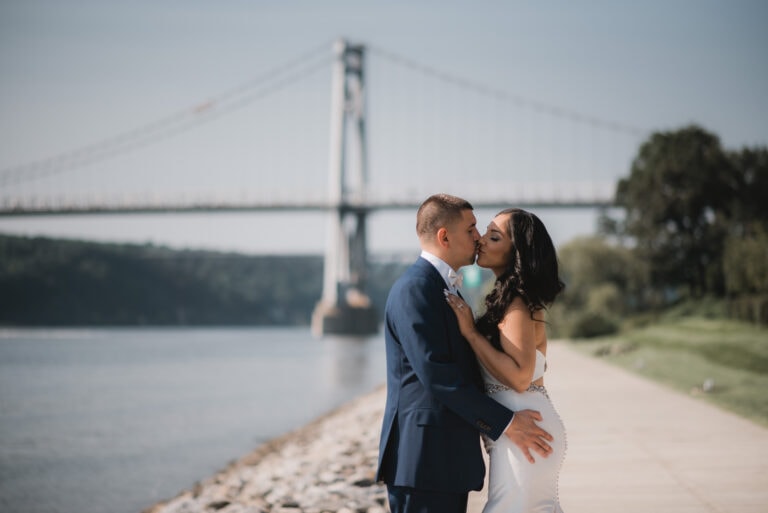 Bride poses by bridge on hudson river at a Hudson Valley Wedding at The Grandview in Poughkeepsie