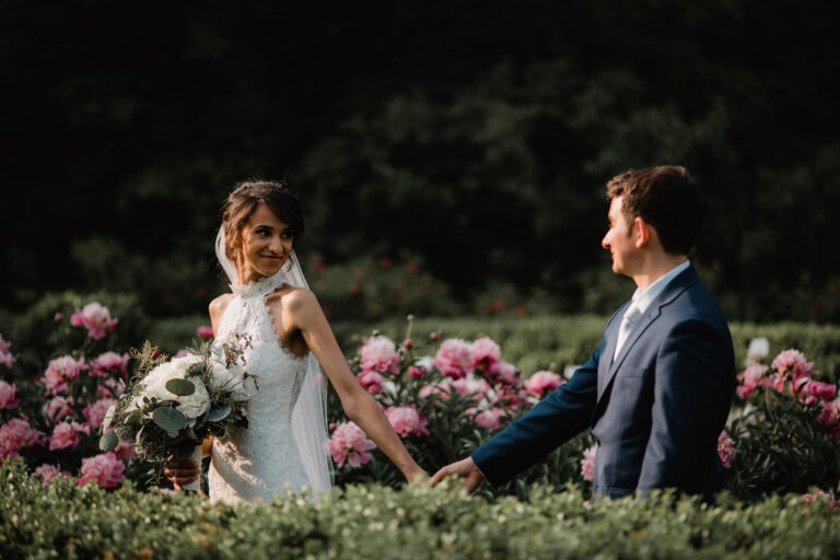 Bride walks with groom in flower garden at a Hudson Valley Wedding at Locust Grove Estate