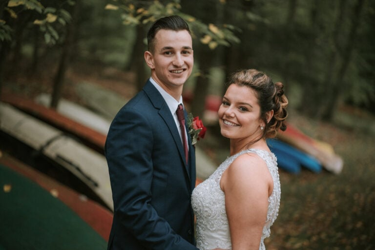 Bride and groom pose for photo along path of boats at a Hudson Valley Wedding at Sedgewick Golf Club