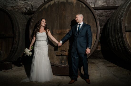 Bride and Groom pose by wine barrels at a Hudson Valley Wedding at the Brotherhood Winery