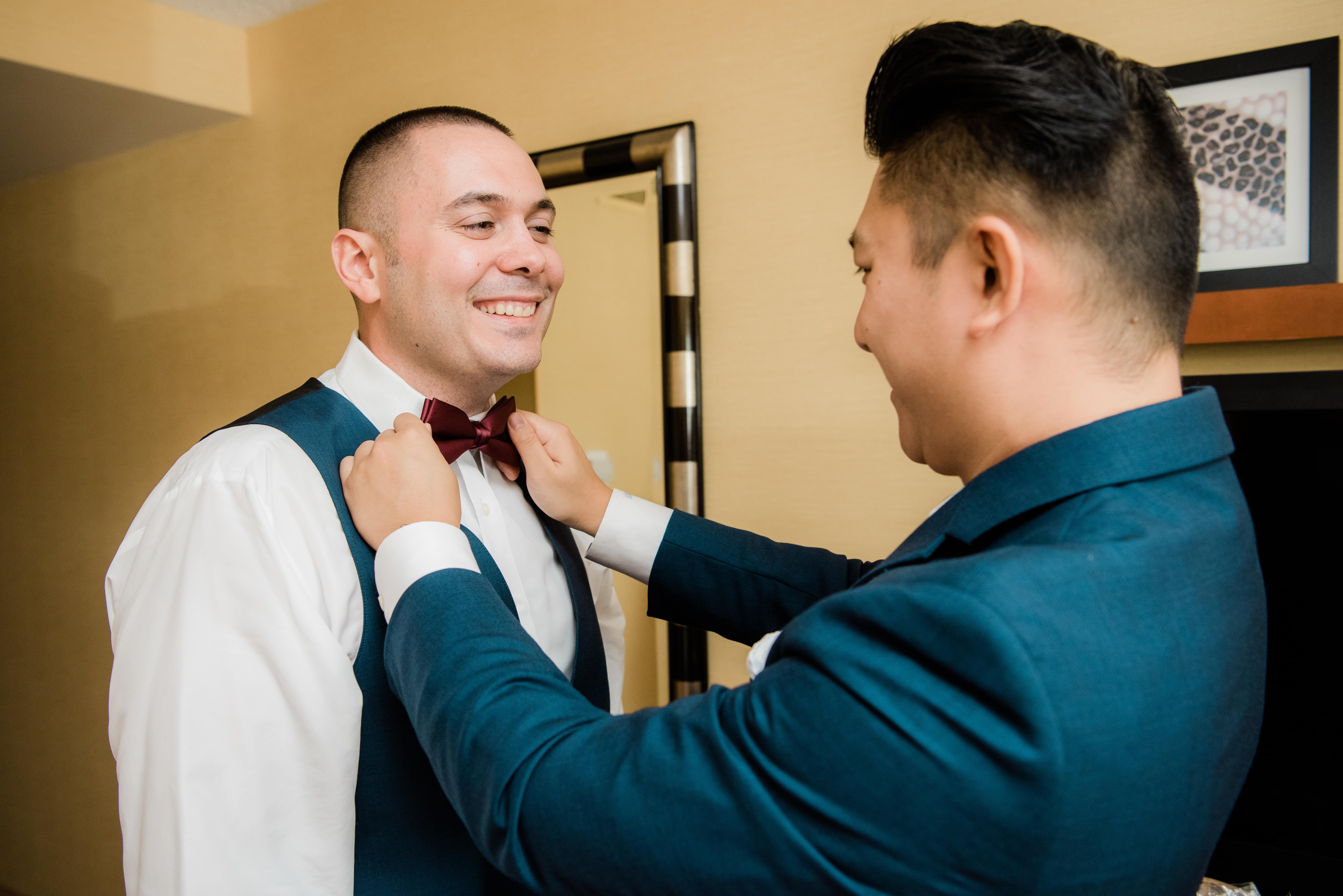 Best man helps groom while getting ready at a Hudson Valley Wedding at Brotherhood Winery