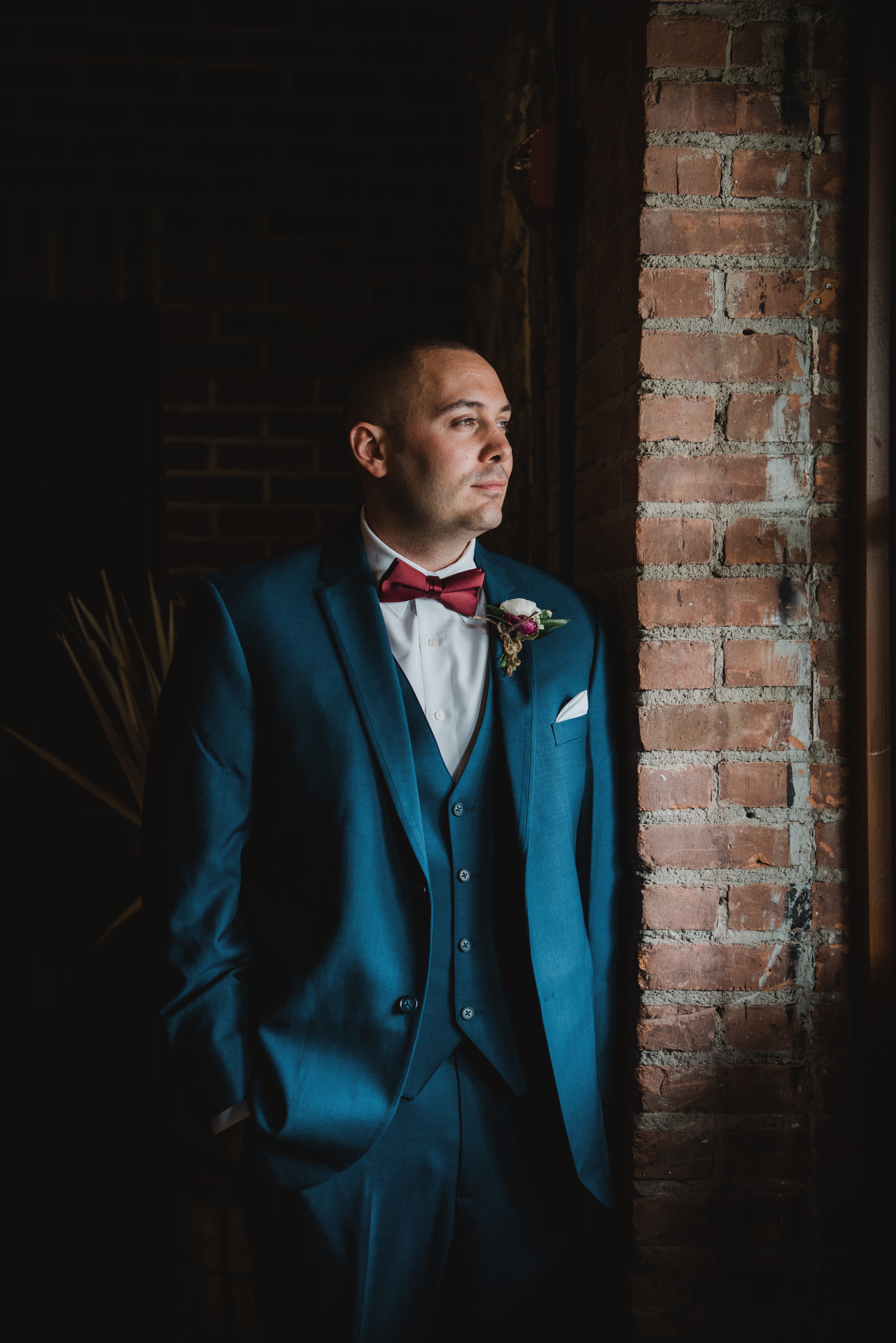 Groom poses by window at a Hudson Valley Wedding at Brotherhood Winery