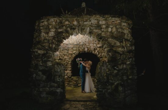 Bride and Groom kiss under stone arbor at a Hudson Valley Wedding at The Garrison