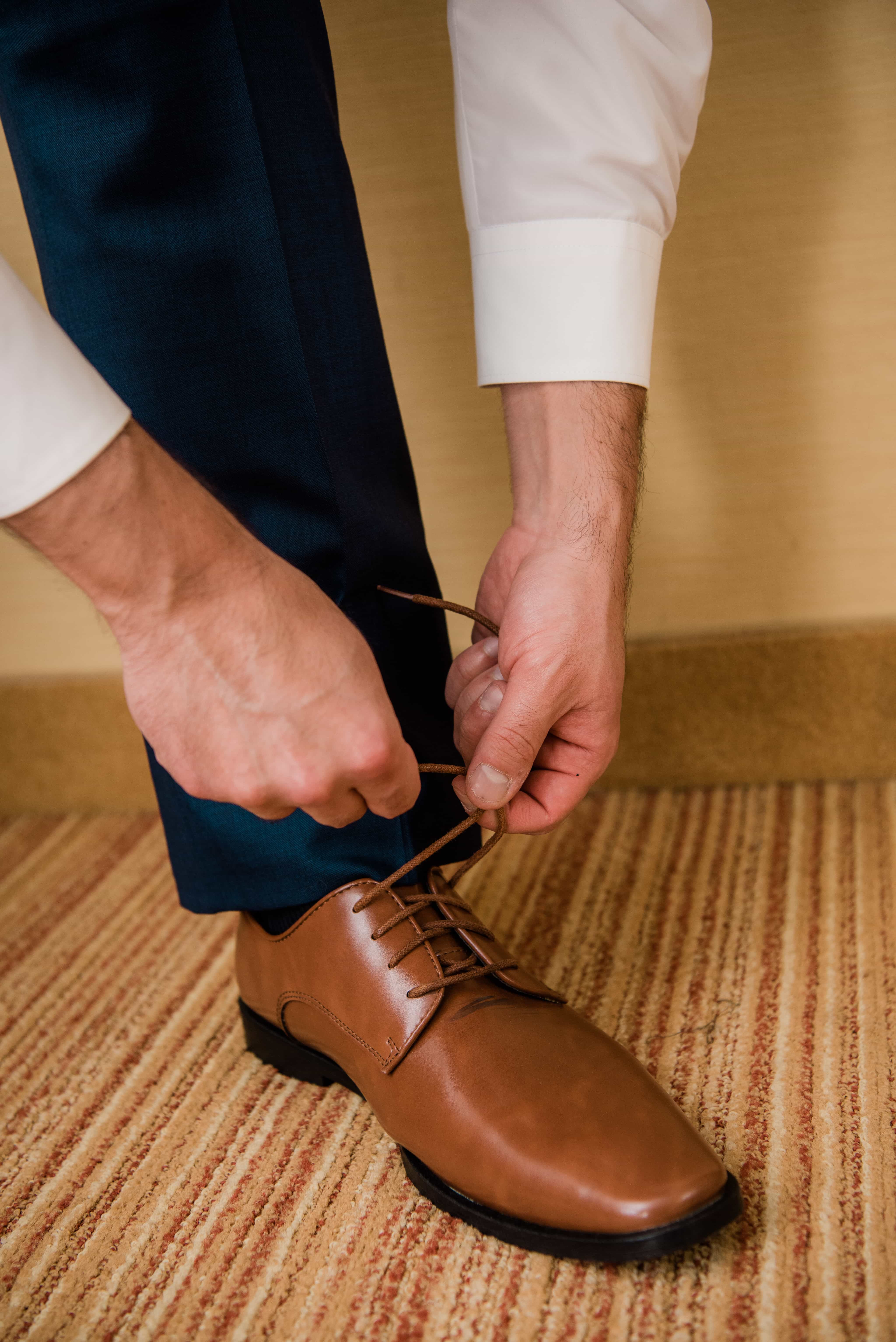 Groom ties shoes while getting ready at a Hudson Valley Wedding at Brotherhood Winery