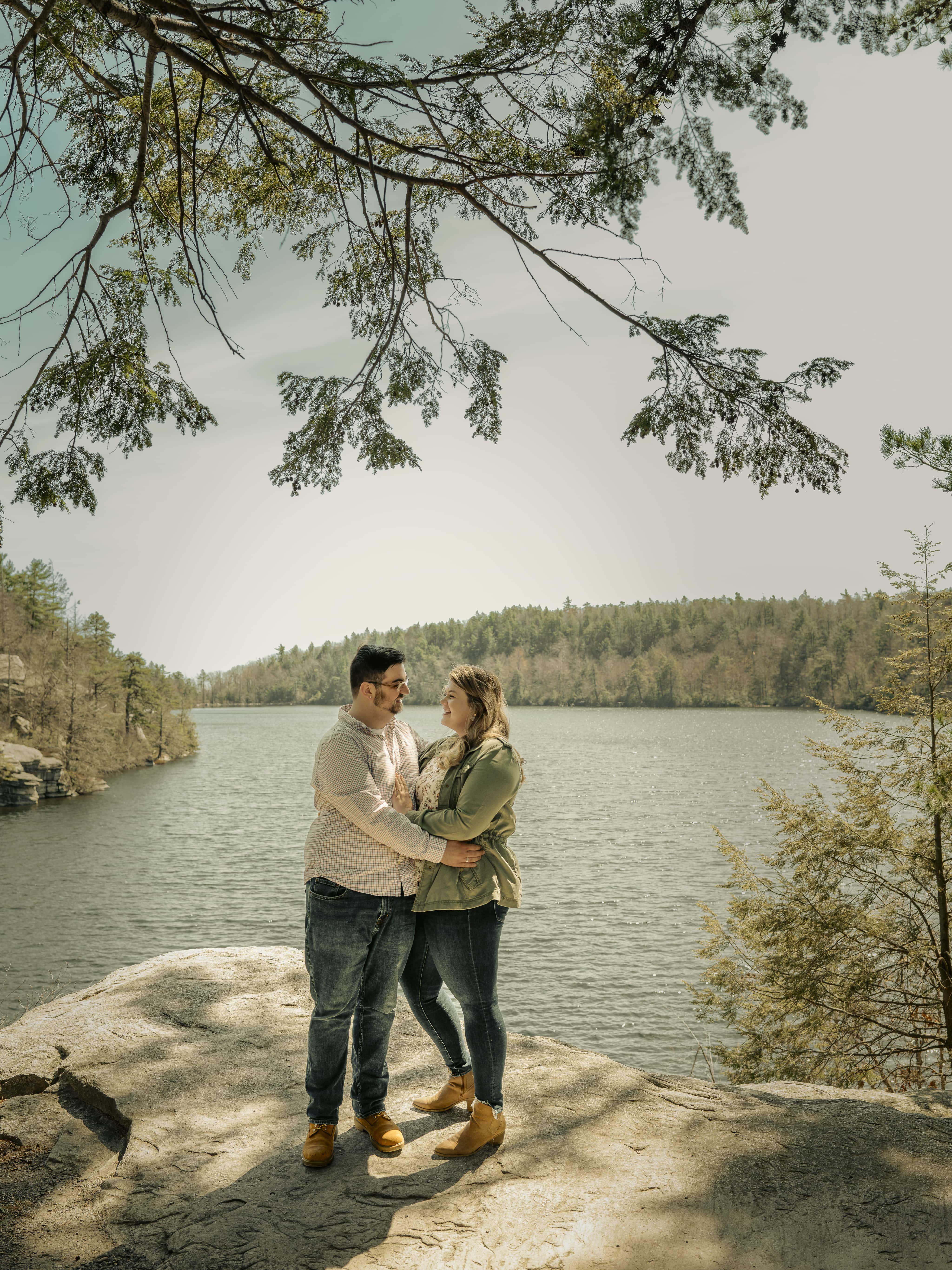 Bride and groom kiss on cliff above lake for Lake Minnewaska Engagement Photos in The Hudson Valley