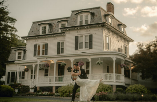 Groom dips bride in front of manor at a Hudson Valley Wedding at Mountainville Manor