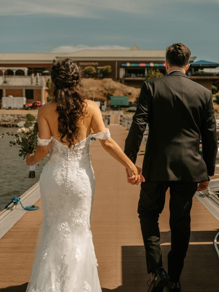 Bride and Groom hold hands and walk on pier at a Grandview Wedding in the Hudson Valley
