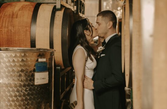 bride and Groom kiss in between wine barrels at a Hudson Valley Wedding at The Brooklyn Winery