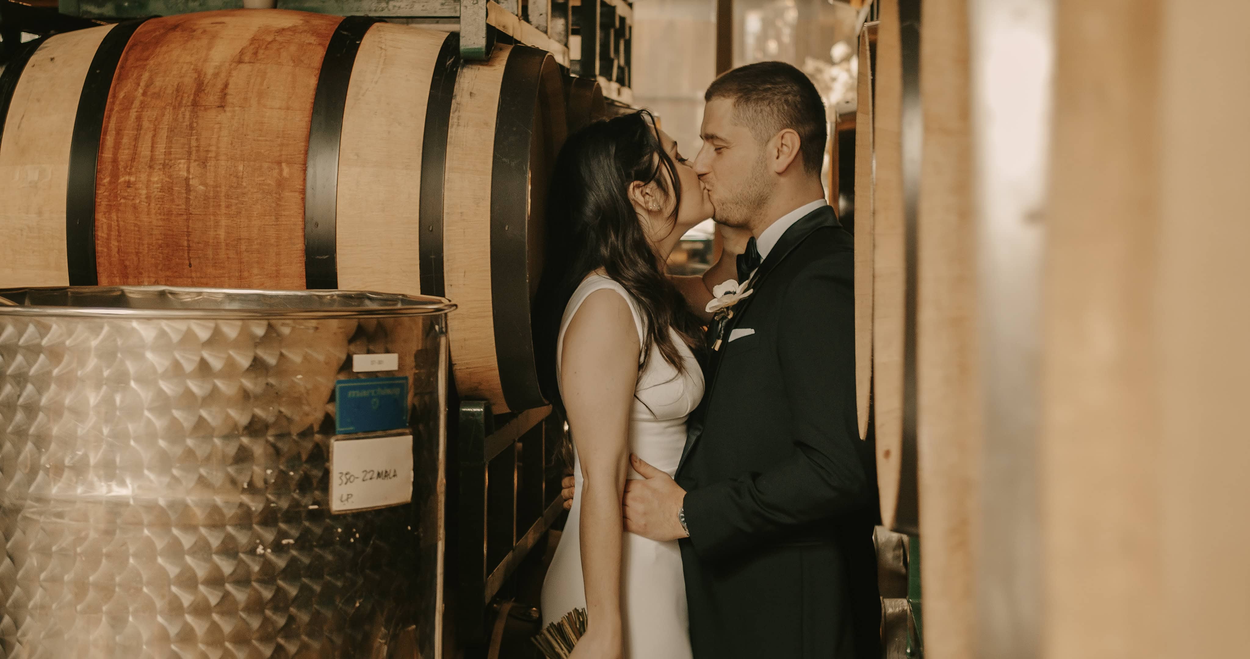 bride and Groom kiss in between wine barrels at a Hudson Valley Wedding at The Brooklyn Winery