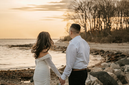Bride andGroom Hold Hands and look away on a beach for an Engagement Photo at Greenwich Point Park in Greenwich Connecticut