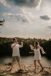 Bride and Groom dance along a cliff by a lake for a Hudson Valley Engagement Photo in Minnewaska State Park