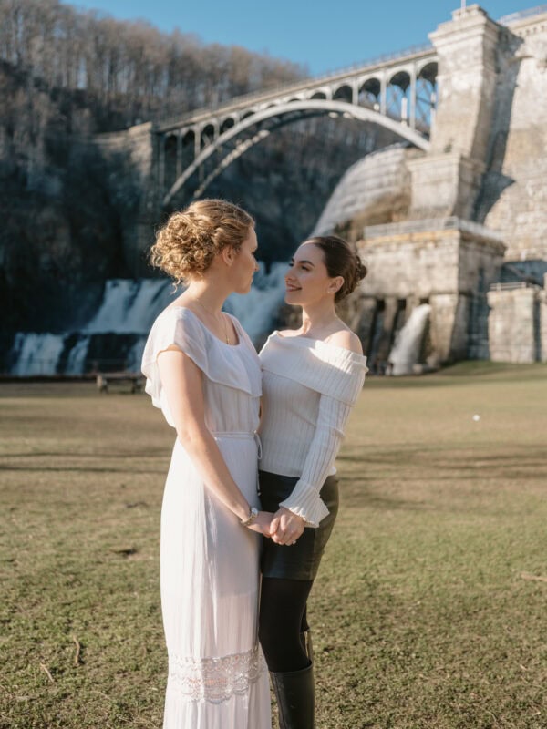 Brides hold hands by waterfall at a Croton Gorge Park Engagement Shoot in the Hudson Valley