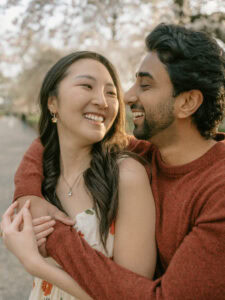 Bride and Groom hug down a Cherry Blossom Path for a Central Park Engagement Shoot in New York City