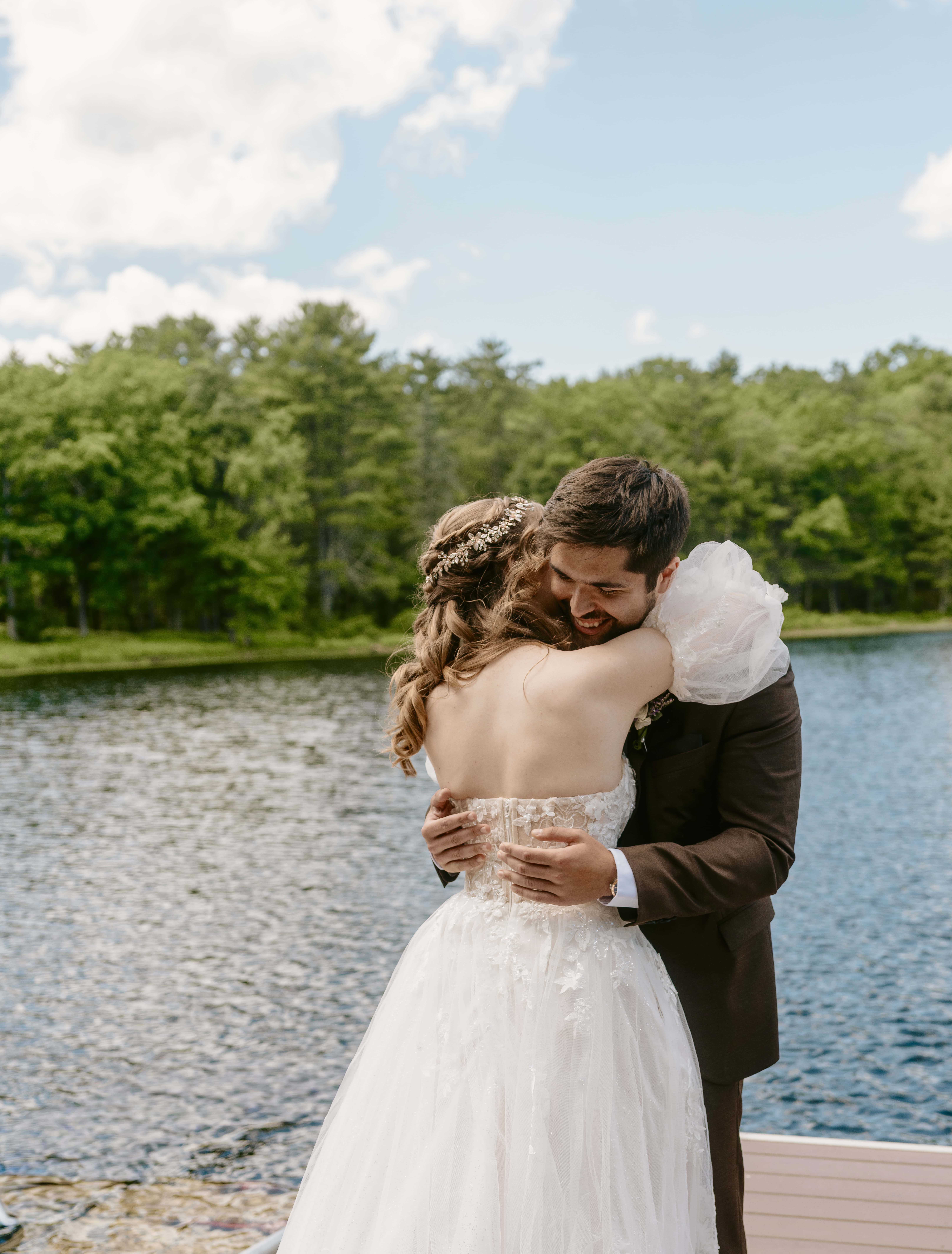 Bride and groom hug on dock by lake for a Hudson Valley Wedding Photo at The Eldred Preserve in the Catskills
